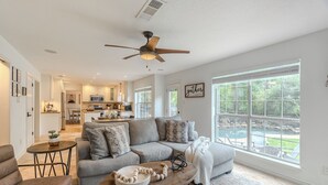A spacious living area with a grey sofa, a coffee table, and a view of a backyard with a pool. - Resort-Style Pool + Spa + BBQ. Spacious 4 bdr Home @The Woodlands (Spring)