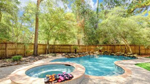 A backyard with a hot tub, a swimming pool, and a wooden fence. - Resort-Style Pool + Spa + BBQ. Spacious 4 bdr Home @The Woodlands (Spring)
