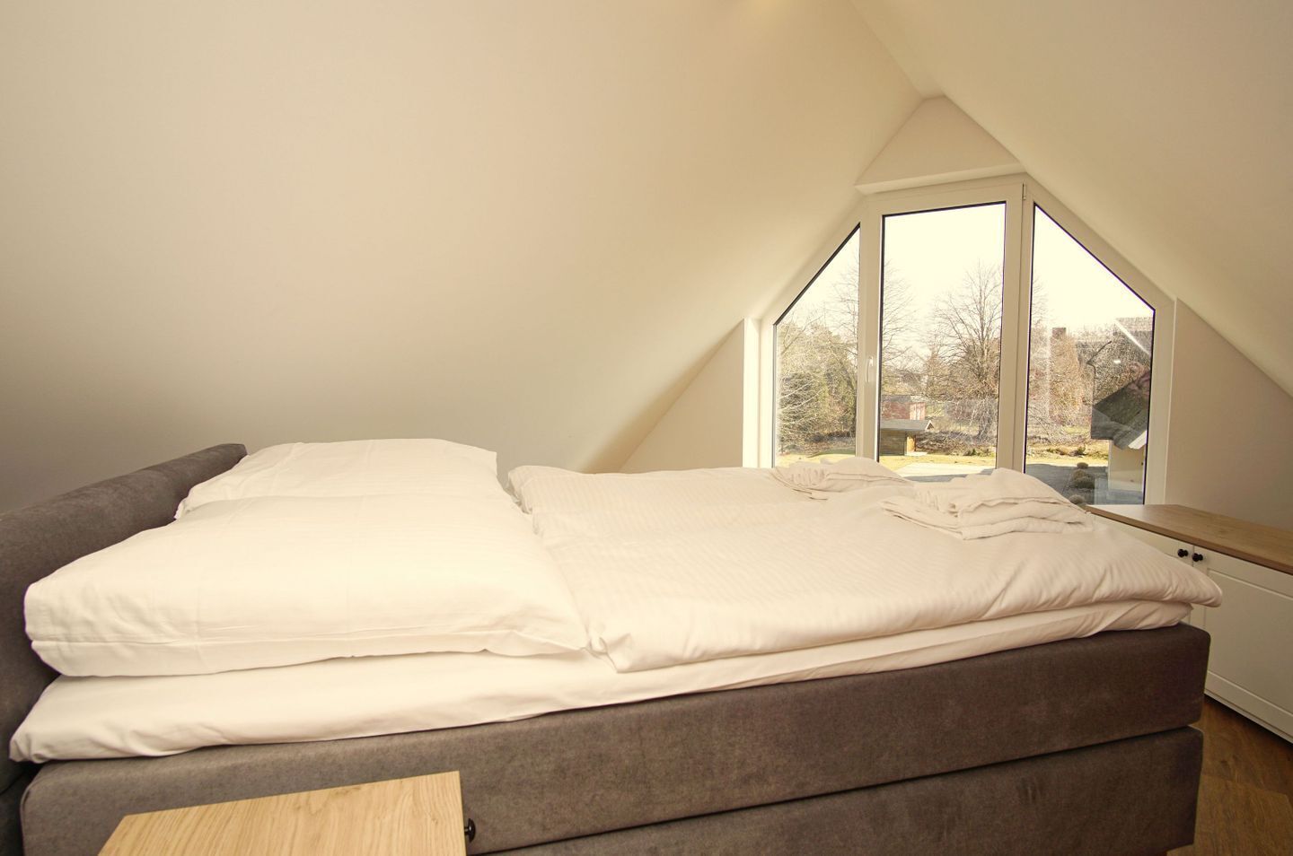 A bedroom with a bed, a window, and a view of the outside.
