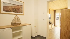A hallway with a wooden floor, a white door, a framed picture on the wall, and a small ship model on a shelf. - Strandhaus Anni - comfortable and modern vacation home - Strandhaus Anni (Mönchgut)