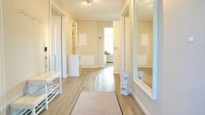 En hall med en bänk, en spegel och en dörr som leder till ett badrum.