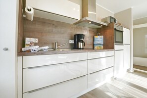 A modern kitchen with a wooden countertop, stainless steel appliances, and a built-in oven. - Strandglück Apartment 1C - Strandglück House C (Scharbeutz)