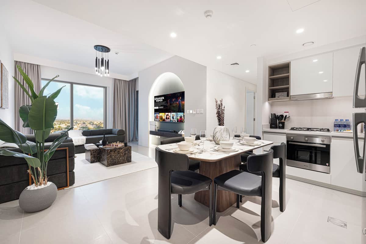 Una cocina moderna con armarios blancos, un comedor con mesa de mármol y un amplio ventanal con vistas.