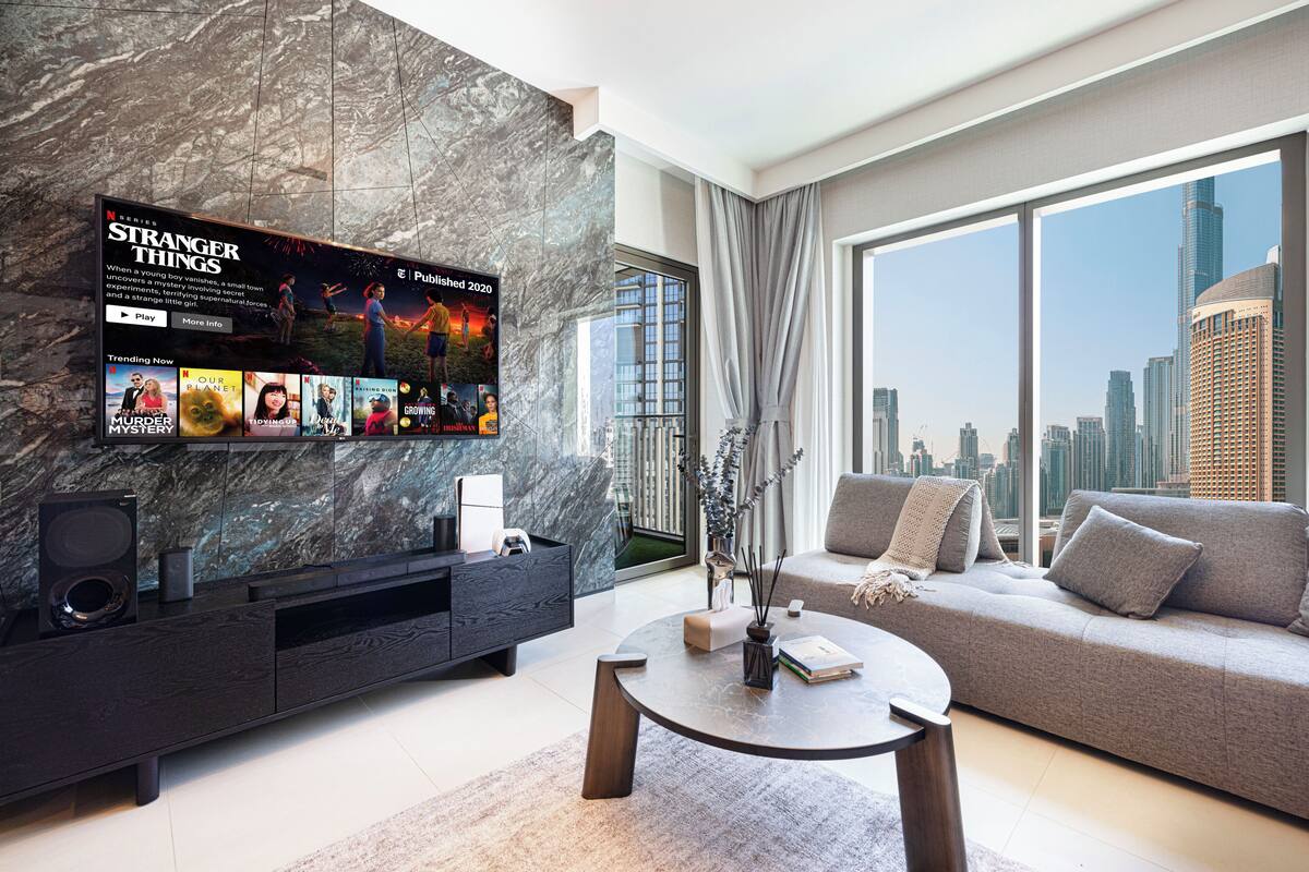 Una sala de estar moderna con un televisor de pantalla plana grande, un sofá, una mesa de centro y una pared decorativa de mármol.