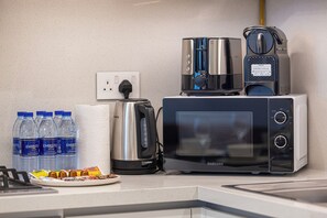 A kitchen with a microwave, toaster, kettle, and bottled water. - Luxury Stays @ Downtown Views 2 with UniDwellers Holiday Homes (Dubai)