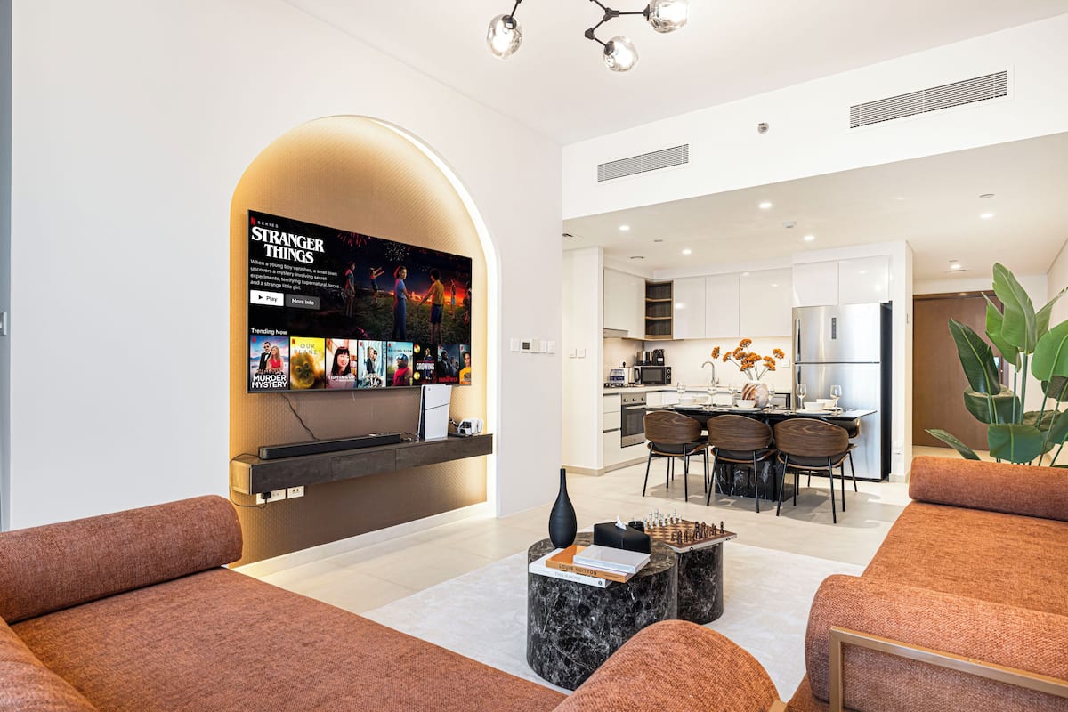 Una sala moderna con televisor de pantalla plana, asientos cómodos, zona de comedor y cocina.