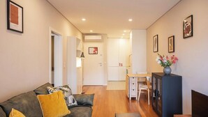 Uma sala de estar moderna com um sofá, uma televisão e um espaço de jantar com mesa e cadeiras.