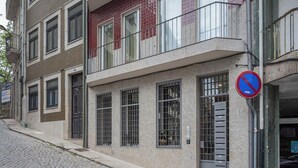 Um edifício de vários andares com placa de proibido estacionar, um portão de metal e rua de calçada.
