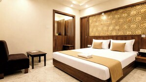 Quarto de hotel com uma cama grande, uma cadeira, uma mesinha e um guarda-roupa.