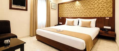 A hotel room with a large bed, a TV mounted on the wall, a desk, and a chair.