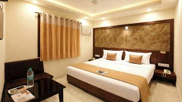 Habitación de hotel con cama, mesita de noche, escritorio, silla, botella de agua y control remoto.