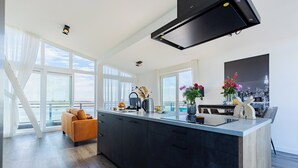 Eine moderne Küche mit einer großen Kochinsel, einem Essbereich mit einer Couch und Blick auf die Stadt.