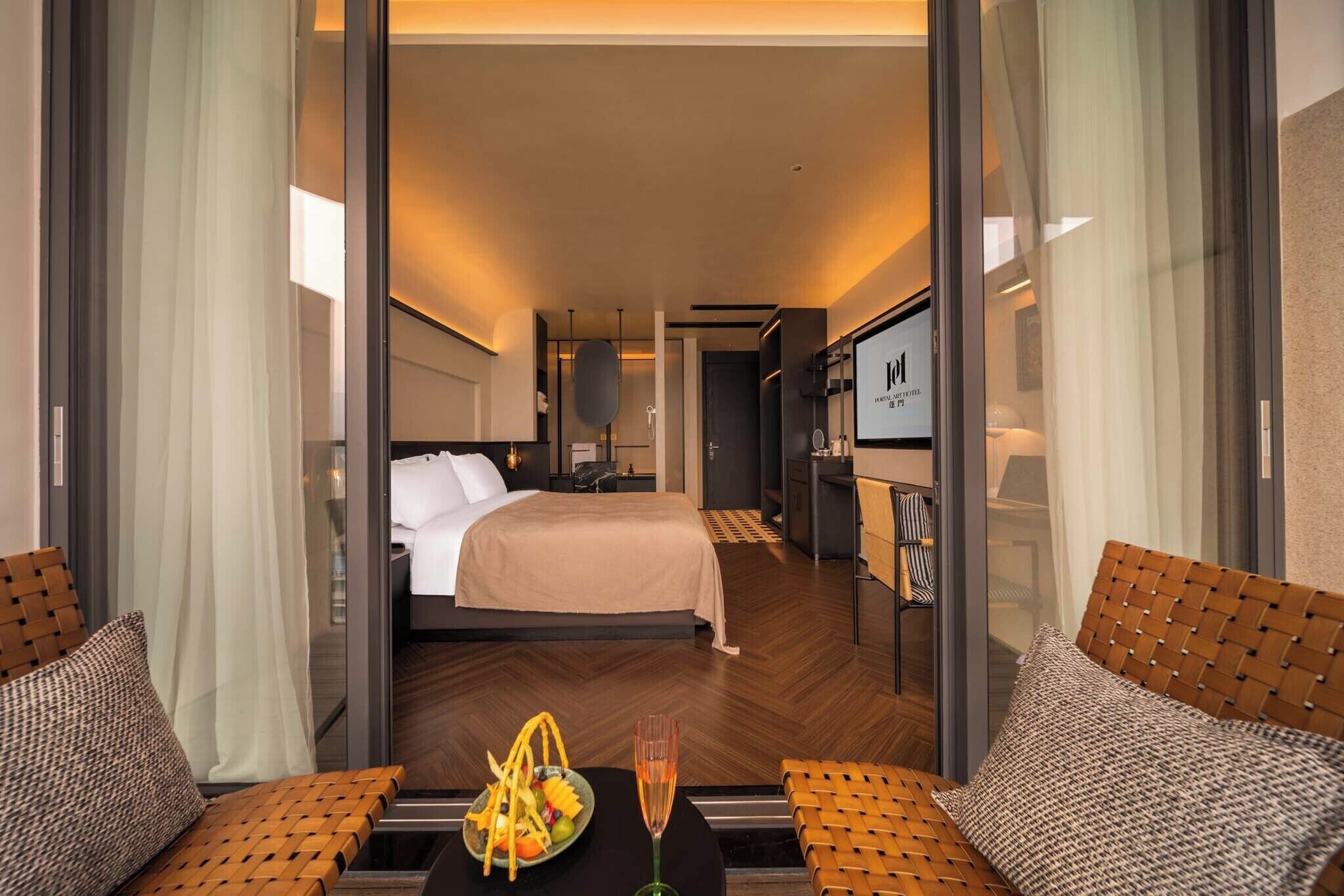 A hotel room with a bed, a TV, a minibar, and a seating area with a table and chairs.