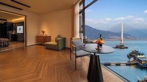Une chambre d’hôtel moderne dotée d’une grande fenêtre donnant sur un pont et sur l’eau.