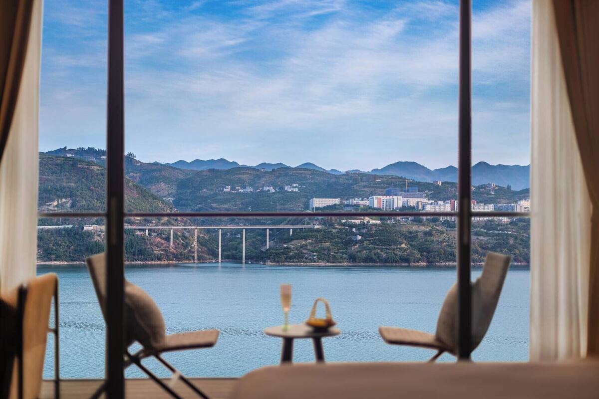 Une pièce dotée d’une grande fenêtre donnant sur un pont et des collines.
