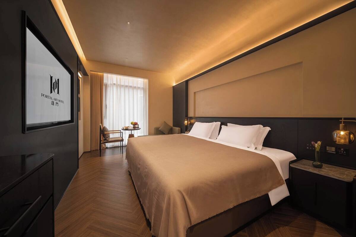 Une chambre d’hôtel avec un grand lit, un bureau, une chaise et un téléviseur fixé au mur.