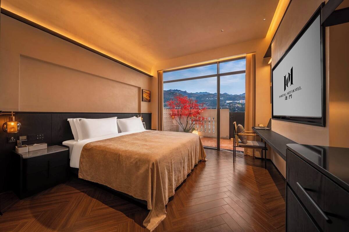 Une chambre d’hôtel avec un lit, une table de chevet, une télévision et une vue sur la ville.