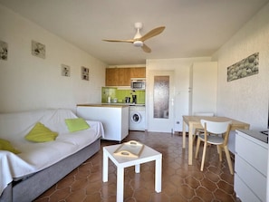 A compact living space with a sofa, a small table, a dining area with chairs, a kitchen with a microwave, and a washing machine. - One-bedroom apartment with a sleeping nook, air conditioning, and a view of the sea (La Londe-les-Maures)