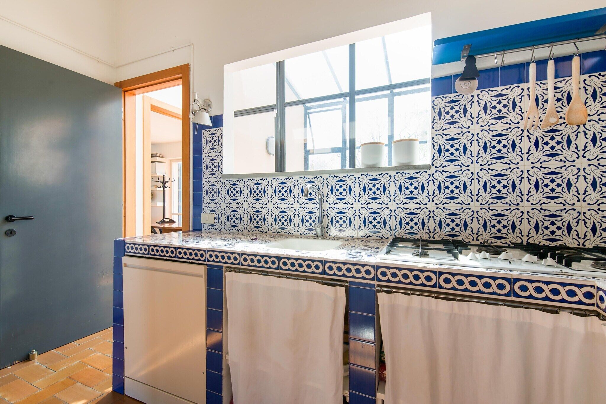 A bathroom with a blue and white tiled wall, a window, and a towel rack.