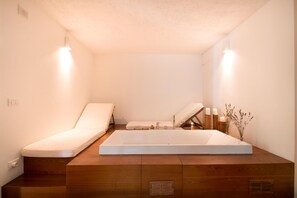 Ein modernes Badezimmer mit einer großen Badewanne, zwei weißen Sitzgelegenheiten und einem Holzbidet.