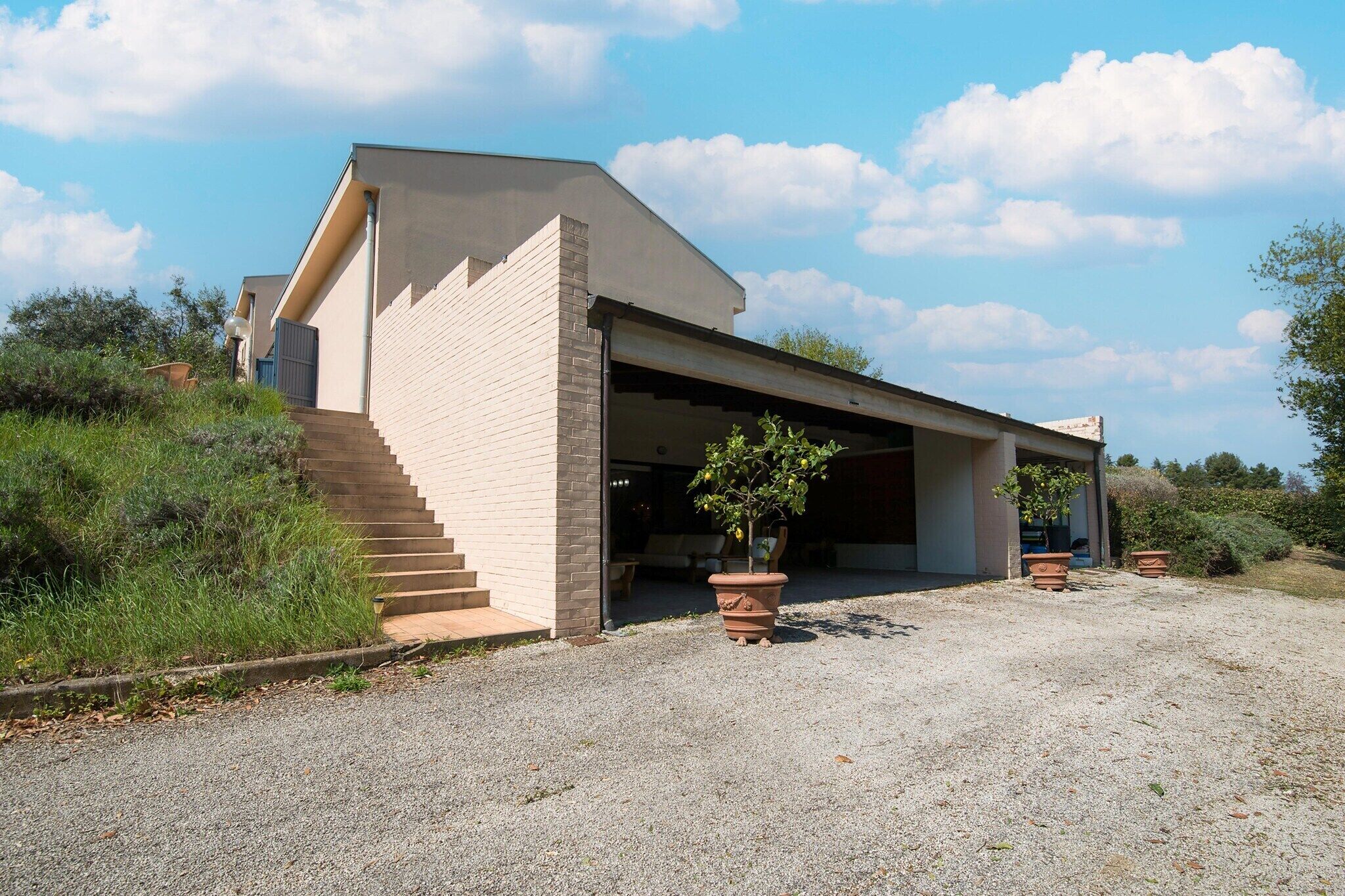 A modern building with a garage, a staircase, and potted plants.