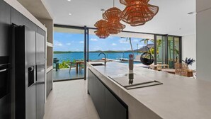 A modern kitchen with a large island, a view of the sea, and a dining area with outdoor seating. - Villa Wave (Willemstad)