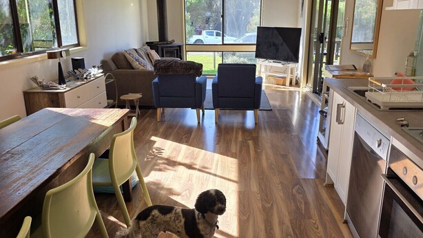 A spacious kitchen with a dining area, a sofa, and a dog. - Where Paris meets Jupiter - Linen, Wi-Fi, Pets OK (Venus Bay)