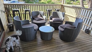 A wooden deck with wicker furniture, including chairs and a round table. - Where Paris meets Jupiter - Linen, Wi-Fi, Pets OK (Venus Bay)