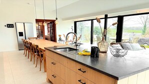 A modern kitchen with a large island, wooden cabinets, and a view of the outdoors. - Luxury Villa with Garden & Zipline (La Roche-en-Ardenne)
