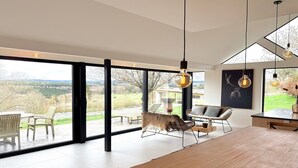 A modern interior with large windows, a dining area, and a view of the outdoors. - Luxury Villa with Garden & Zipline (La Roche-en-Ardenne)