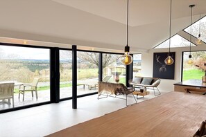 A modern interior with large windows, a dining area, and a view of the outdoors. - Luxury Villa with Garden & Zipline (La Roche-en-Ardenne)