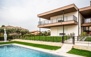 A modern two-story house with a swimming pool, outdoor seating, and a giraffe statue. - Art&Fashion- Ariom Apartments (Moniga del Garda)