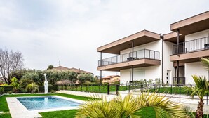 A modern two-story building with balconies, a swimming pool, and surrounding greenery. - Pop Vibes - Ariom Apartments (Moniga del Garda)
