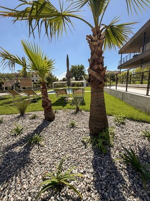 Un espace aménagé avec des palmiers, une piscine et un bâtiment doté d’un balcon.