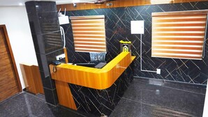 Un'area reception con un bancone in legno, una parete in marmo nero e una ventola a soffitto.