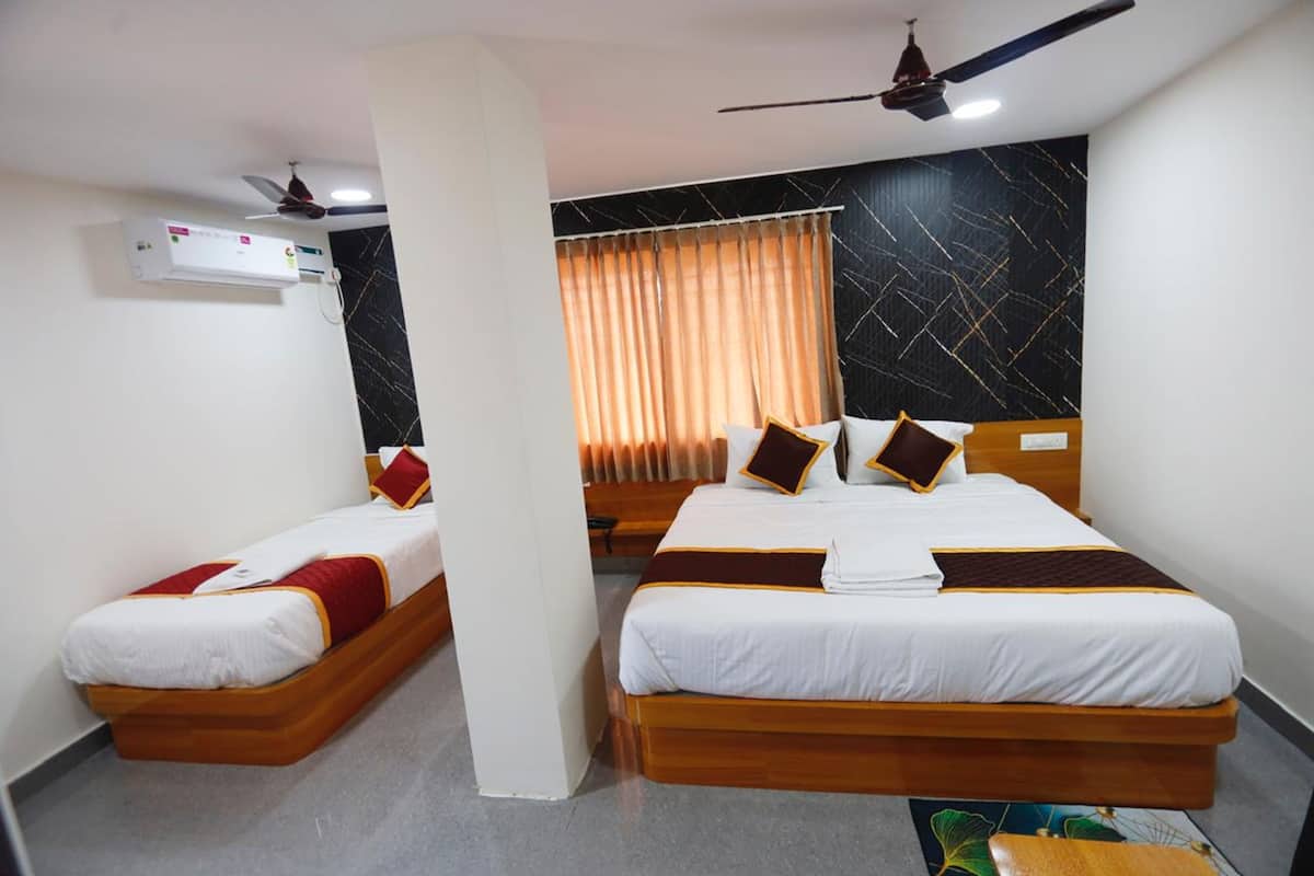 A hotel room with two beds, a ceiling fan, an air conditioning unit, and a window with curtains.
