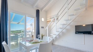 A modern interior with a dining area, a staircase, and a TV mounted on the wall. - Affittimoderni Castelsardo - Blue Loft (Castelsardo)