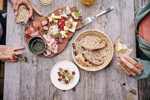 A wooden table with various food items, including meats, cheeses, and bread, suggesting a communal meal setting. - Alvierblick - Colrosa Residence (Brand)