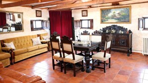 A dining area with a wooden table, chairs, a sofa, and a red curtain.
