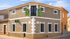 A building with a balcony, multiple windows, and a sign indicating it is a rural house.