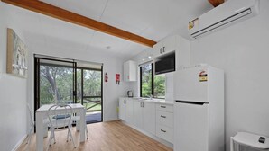 A modern kitchen with white cabinets, a built-in microwave, and a refrigerator. - Agnes Bush Cabins #3 (Round Hill)