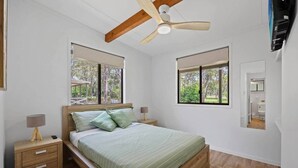 A bedroom with a bed, two bedside tables, a ceiling fan, and two windows. - Agnes Bush Cabins #4 (Round Hill)