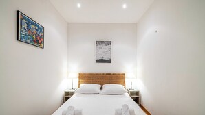 A hotel room with a bed, two bedside tables, a headboard, and two wall-mounted lamps. - Warm Apartment 2P in the heart of Nice - near the sea (Nice)