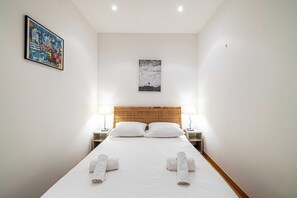 Ein Hotelzimmer mit einem Bett, zwei Nachttischen, einem Kopfteil und zwei Wandlampen.