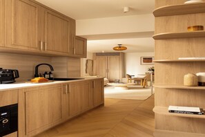 A modern kitchen with wooden cabinets, a coffee machine, and a built-in oven. - Modern Apartment a/c 1CH/4P - Saint -Germain (Paris)