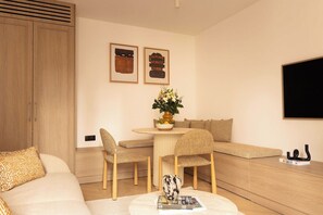 A modern living room with a sofa, a dining table with chairs, a TV mounted on the wall, and a cabinet. - Modern Apartment a/c 1CH/4P - Saint -Germain (Paris)