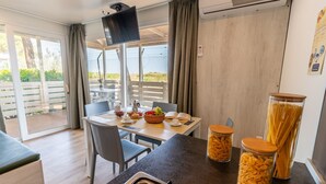 Eine moderne Küche mit Essbereich, Fernseher und Blick ins Freie.
