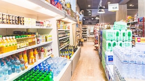 A grocery store aisle with various products on shelves and in bins, including bottled water and beverages. - Jesolo Family Resort (Lido de Jesolo)