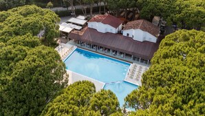 An aerial view of a property with a swimming pool, white buildings, and surrounding trees. - Jesolo Family Resort (Lido de Jesolo)