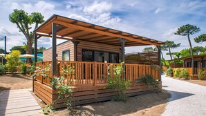 Une cabane en bois dotée d’un porche couvert, d’un chemin de gravier et entourée de végétation.